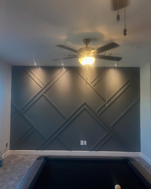 Charcoal accent wall with geometric trim in a finished game room