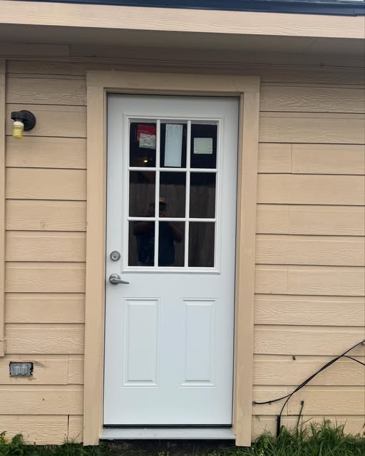 New white nine-lite exterior door installed with fresh casing on lap siding