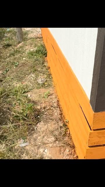 Freshly stained skirting boards along the base of an outbuilding