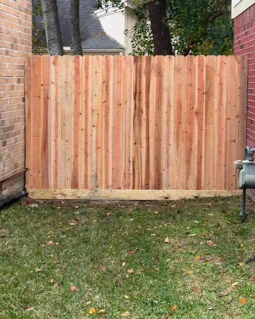 New cedar privacy fence panel with kickboard installed between two homes